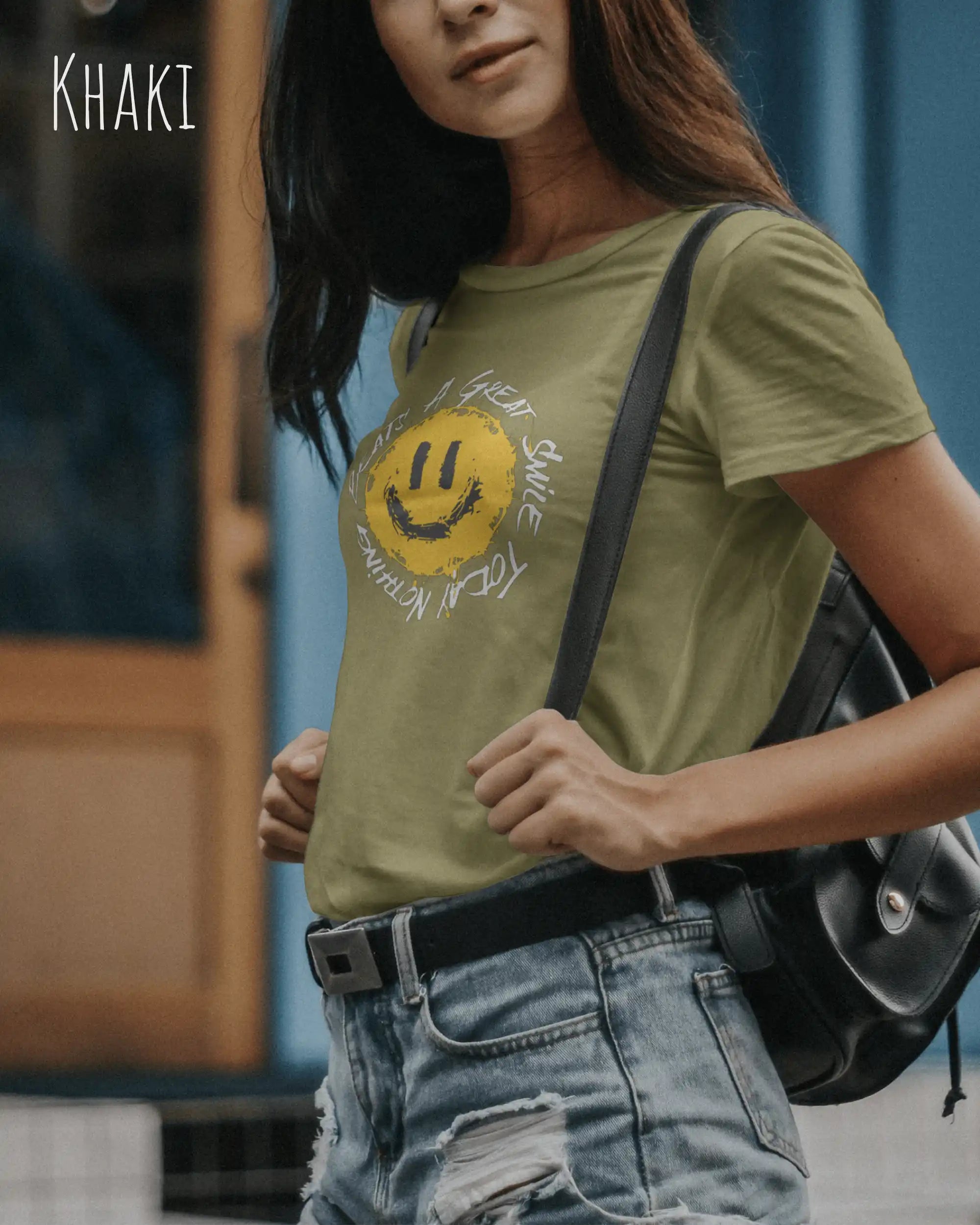 Junge Frau trägt ein Design-T‑Shirt im Feminine Fit in der Farbe khaki.. Das Design zeigt das Statement NOTHING BEATS A SMILE.