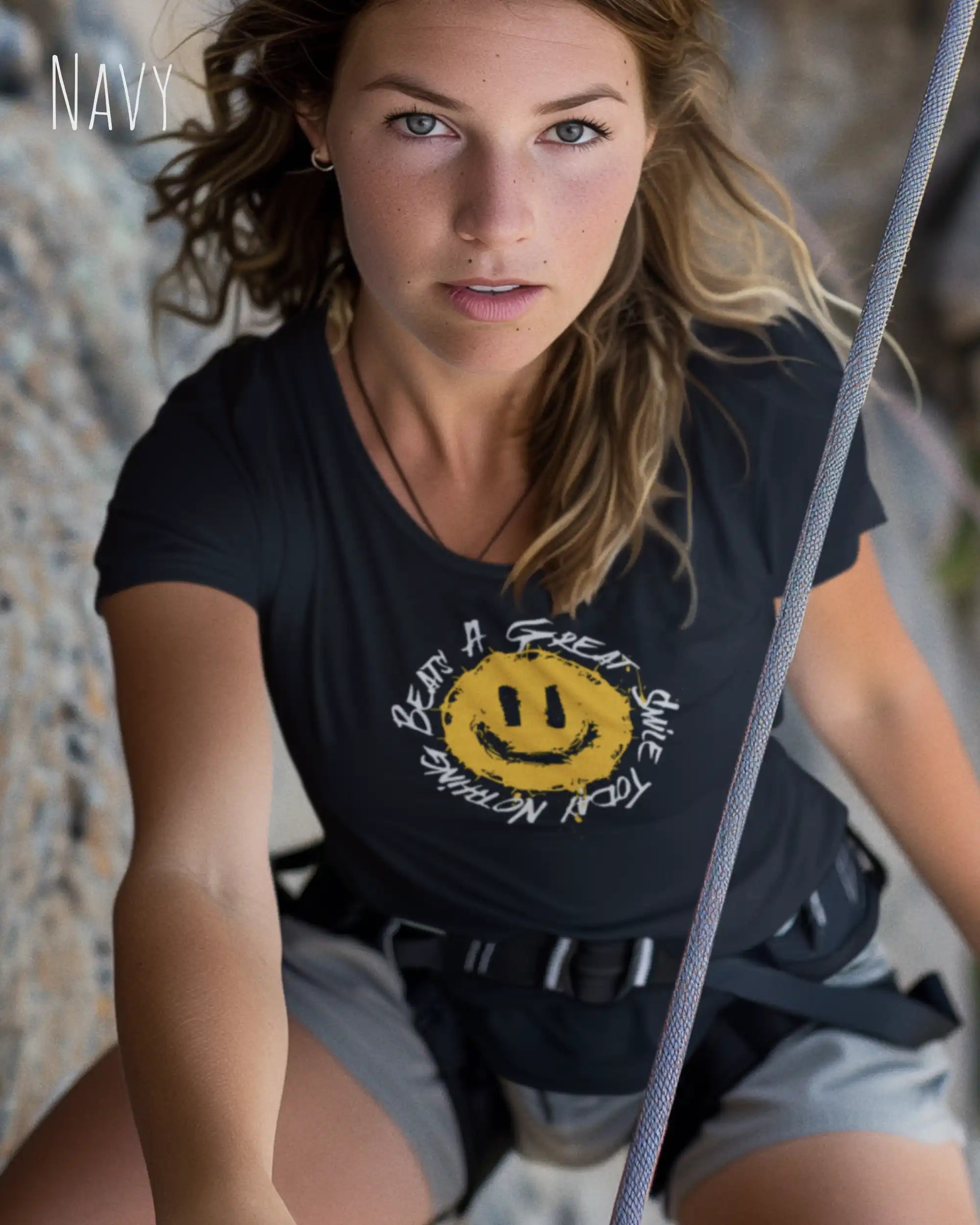 Frau beim klettern trägt ein Design-T‑Shirt im Feminine Fit in der Farbe navy. Das Design zeigt das Statement NOTHING BEATS A SMILE.