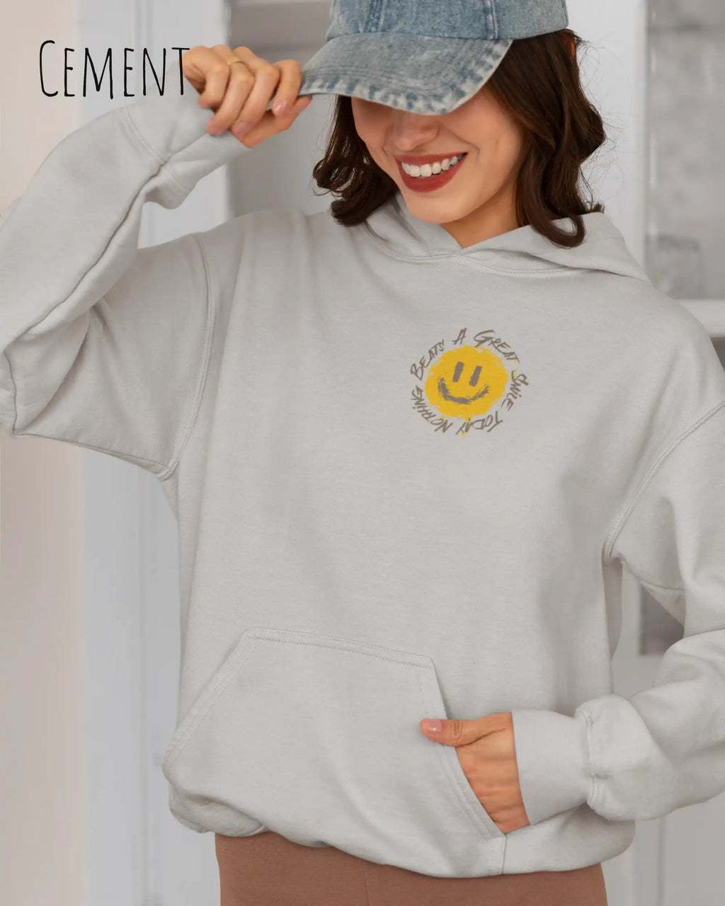 Frau trägt einen Heavyweight oversized Hoodie in cement mit dem Statement-Design Nothing beats a great smile today oben links.