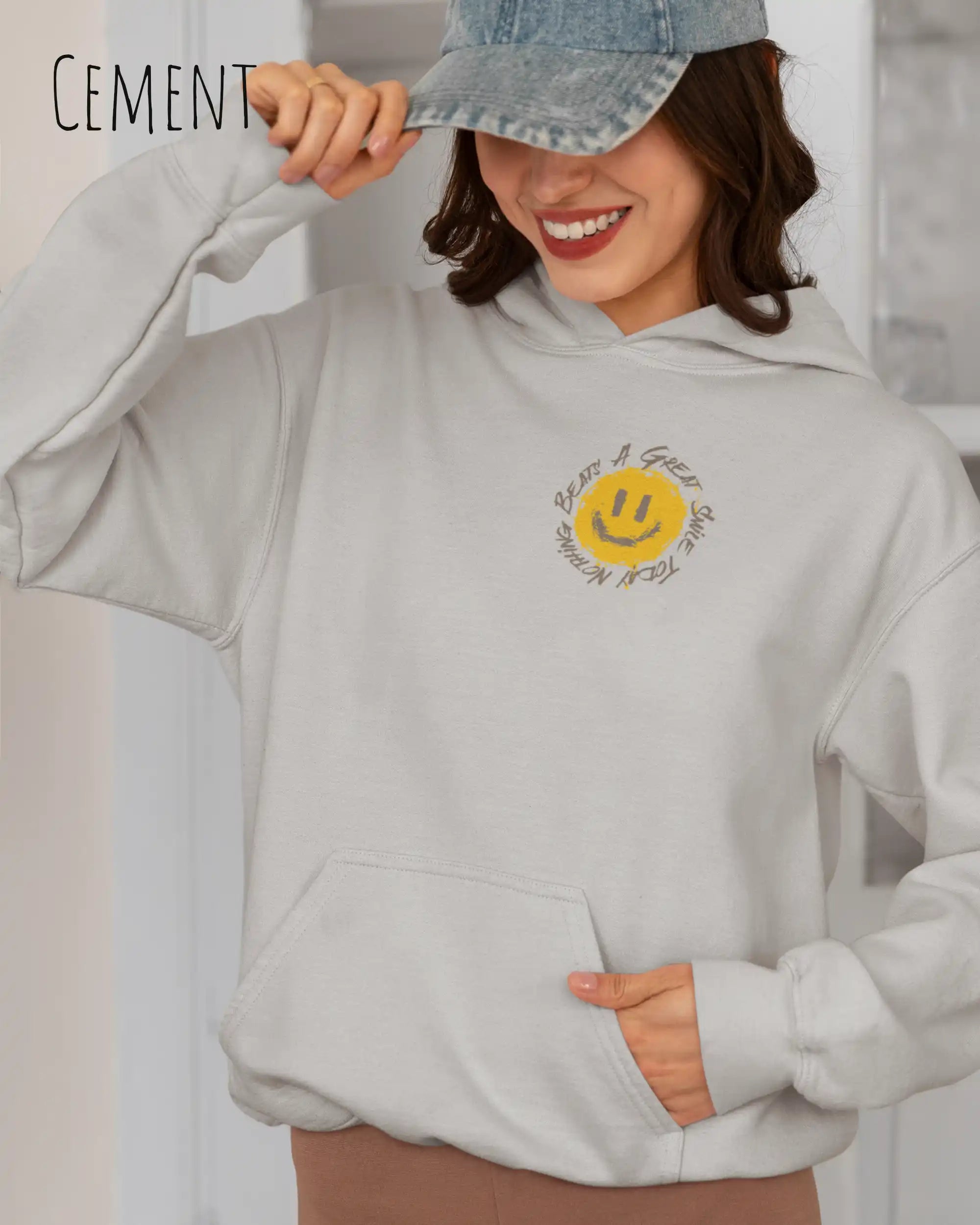 Frau trägt einen Heavyweight oversized Hoodie in cement mit dem Statement-Design Nothing beats a great smile today oben links.