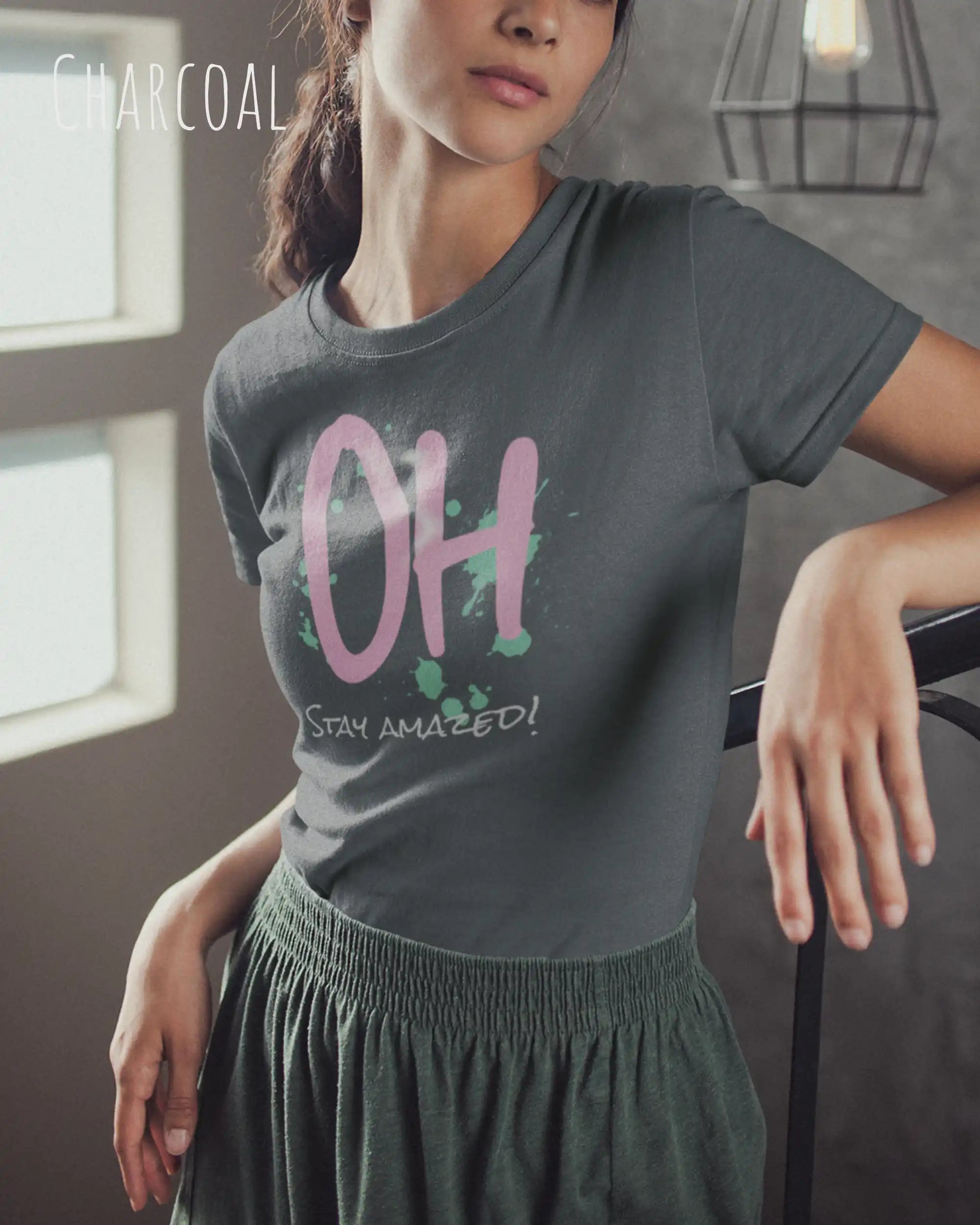 Frau trägt das leichte Sommer T-Shirt aus Baumwolle AWDis 150 T in der Farbe CHARCOAL mit dem Design STAY AMAZED auf der Brust.