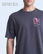 Mann trägt das leichte Sommer T-Shirt aus Baumwolle AWDis 150 T in der Farbe Airforce Blue mit dem Design STAY AMAZED links oben auf der Brust.