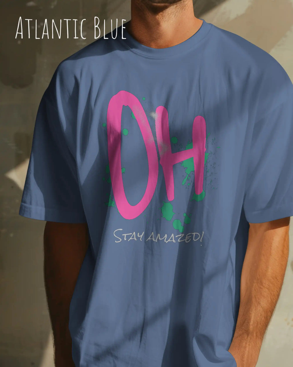 Mann trägt das Heavyweight Oversized T-Shirt AWDis 240 T in der Farbe atlantic blue mit dem Design OH STAY AMAZED auf der Brust.