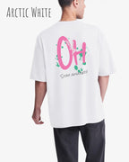 Mann trägt das Heavyweight Oversized T-Shirt AWDis 240 T in der Farbe arctic white mit dem Design OH STAY AMAZED auf dem Rücken.