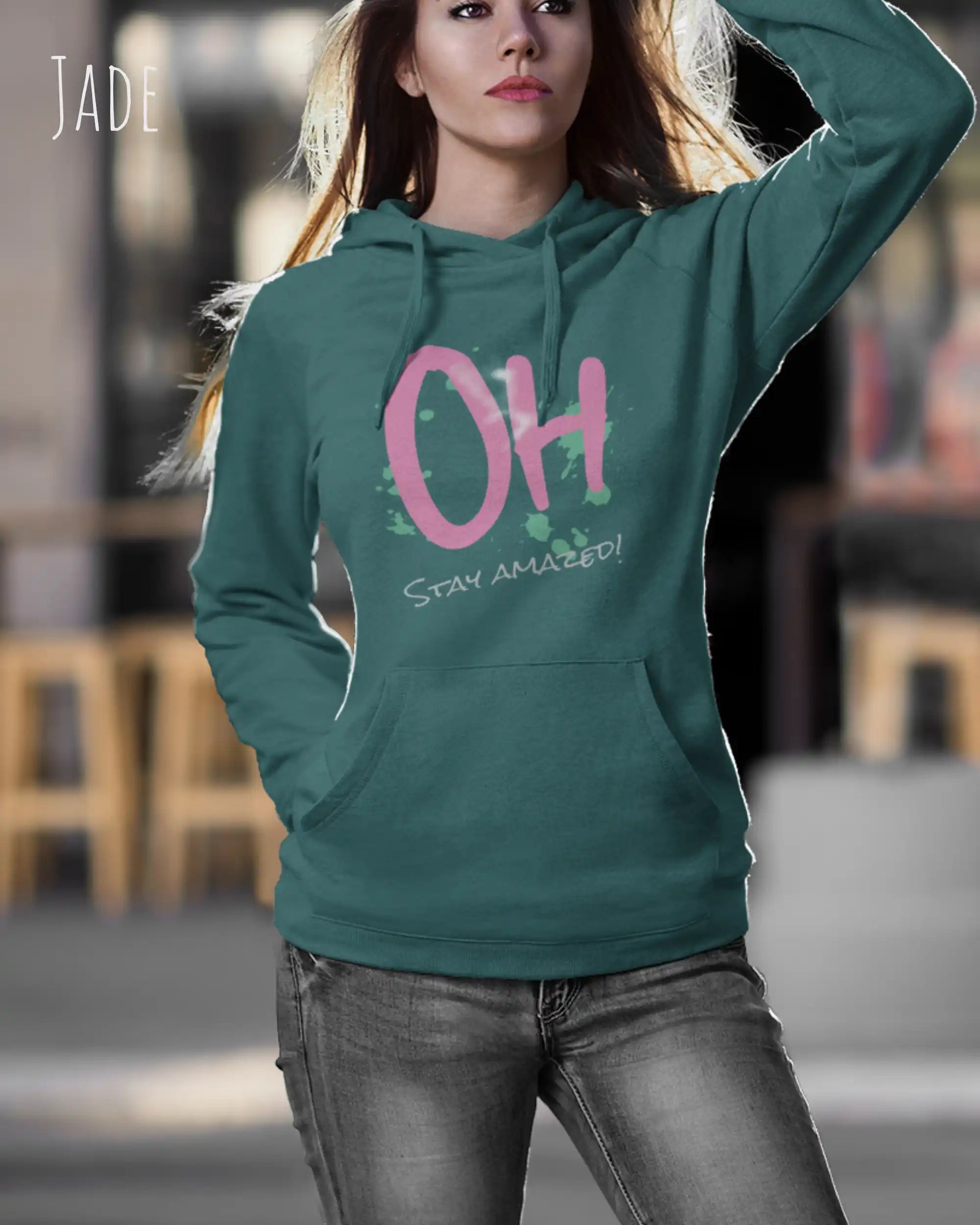 Frau trägt hoodie im feminine fit aus weicher baumwollmischung in farbe jade mit stay amazed motiv auf der Brust