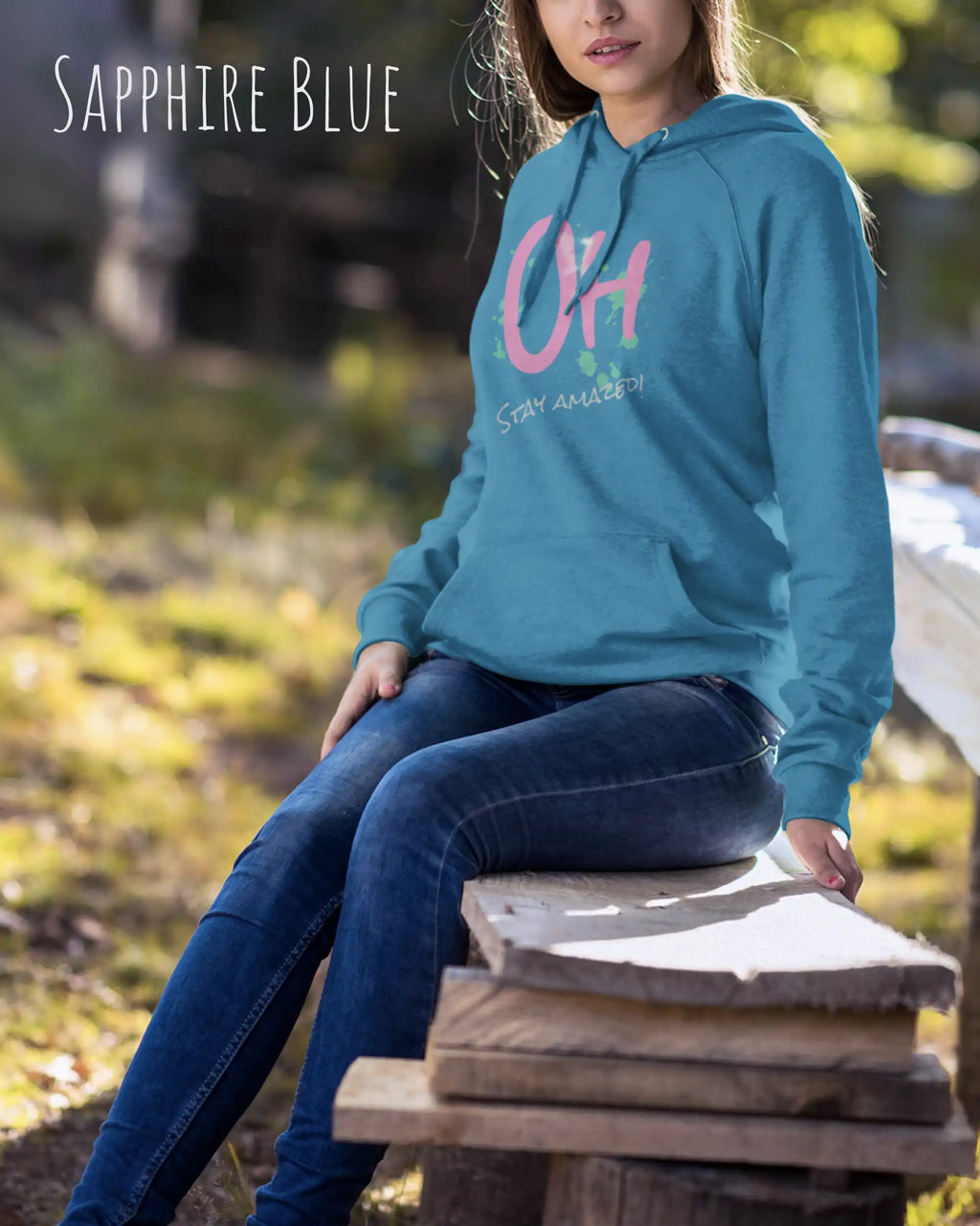 Frau trägt hoodie im feminine fit aus weicher baumwollmischung in farbe sapphire blue mit stay amazed motiv auf der Brust