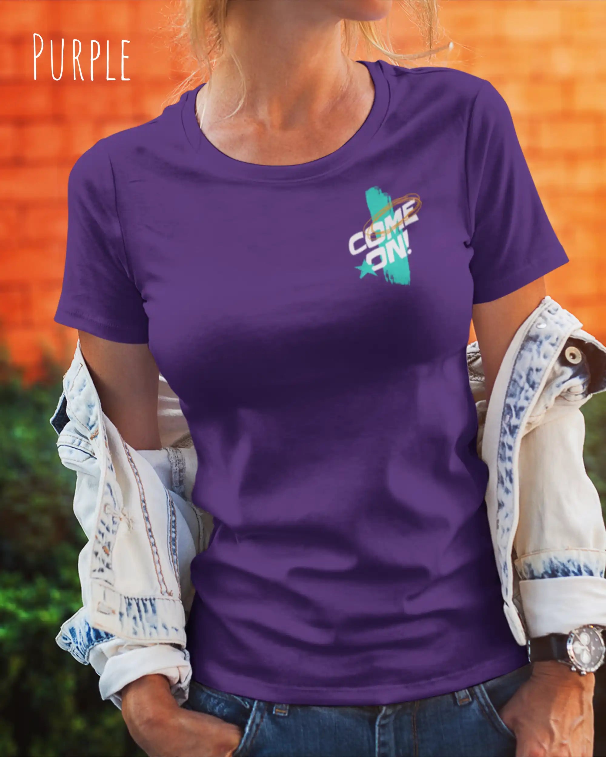Eine Frau trägt ein Unisex-Design-T-Shirt in der Farbe purple mit dem motiv come on vorne links oben.