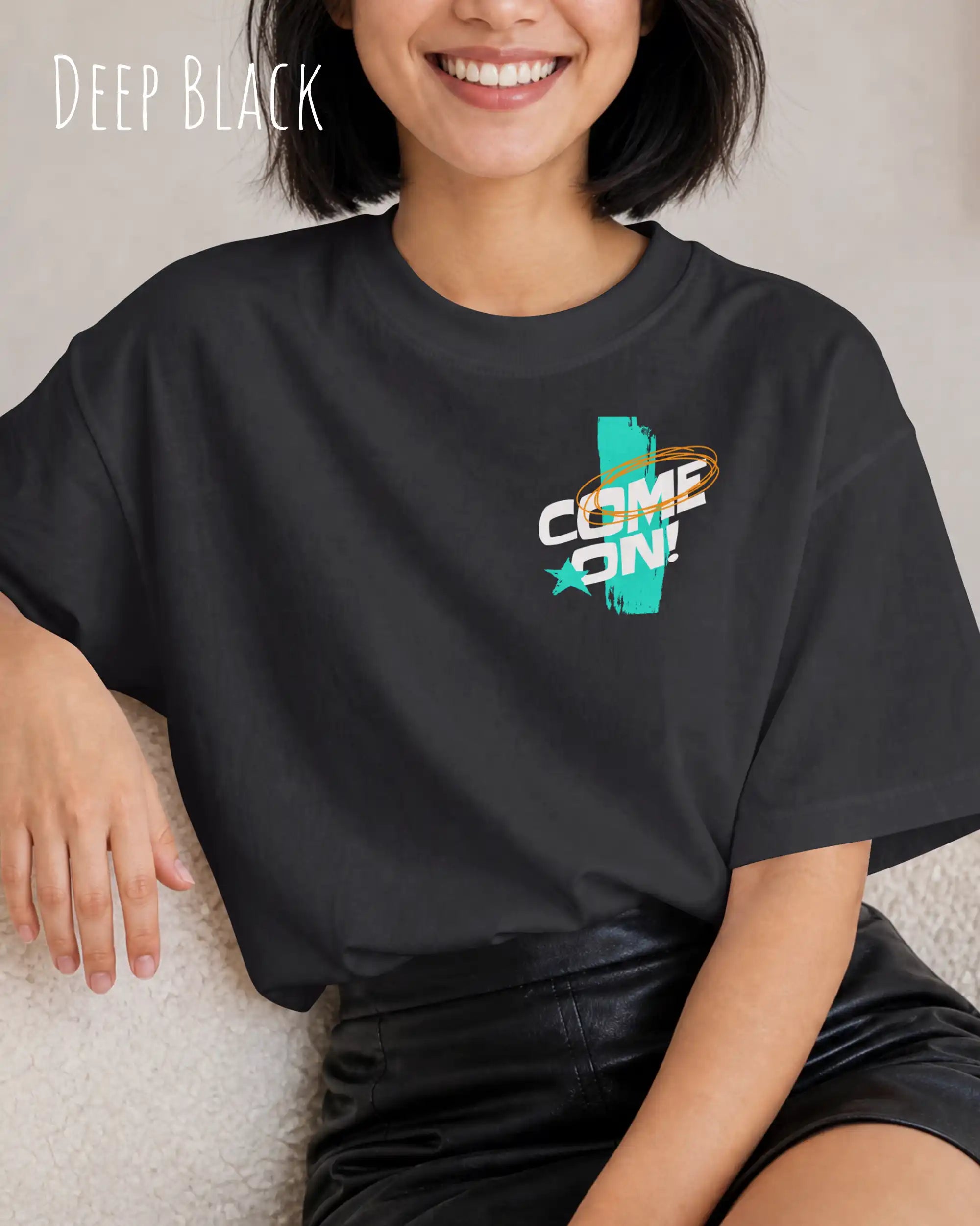 frau trägt  ein oversized heavyweight grafik-t-shirt in der farbe deep black mit dem design come on! oben links