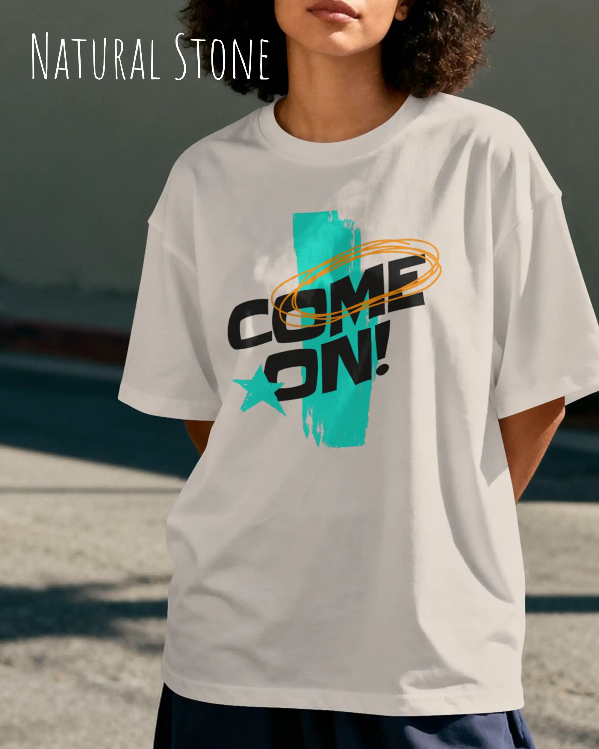 junge frau trägt  ein oversized heavyweight grafik-t-shirt in der farbe natural stone mit dem design come on!