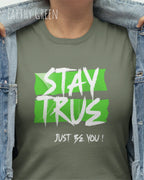 Auf diesem Bild trägt eine frau ein Grafik-t-shirt in der Barbe earthy green  und mit dem design stay true.