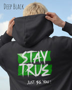das bild zeigt eine Frau, die einen Oversized Design-Hoodie in der farbe deep black mit dem ausdrucksstarken motiv "stay true ... just be you" auf dem rücken trägt.