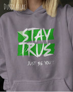 das bild zeigt eine blonde frau, die einen Oversized Design-Hoodie in der farbe dusty lilac mit dem ausdrucksstarken motiv "stay true ... just be you" trägt.
