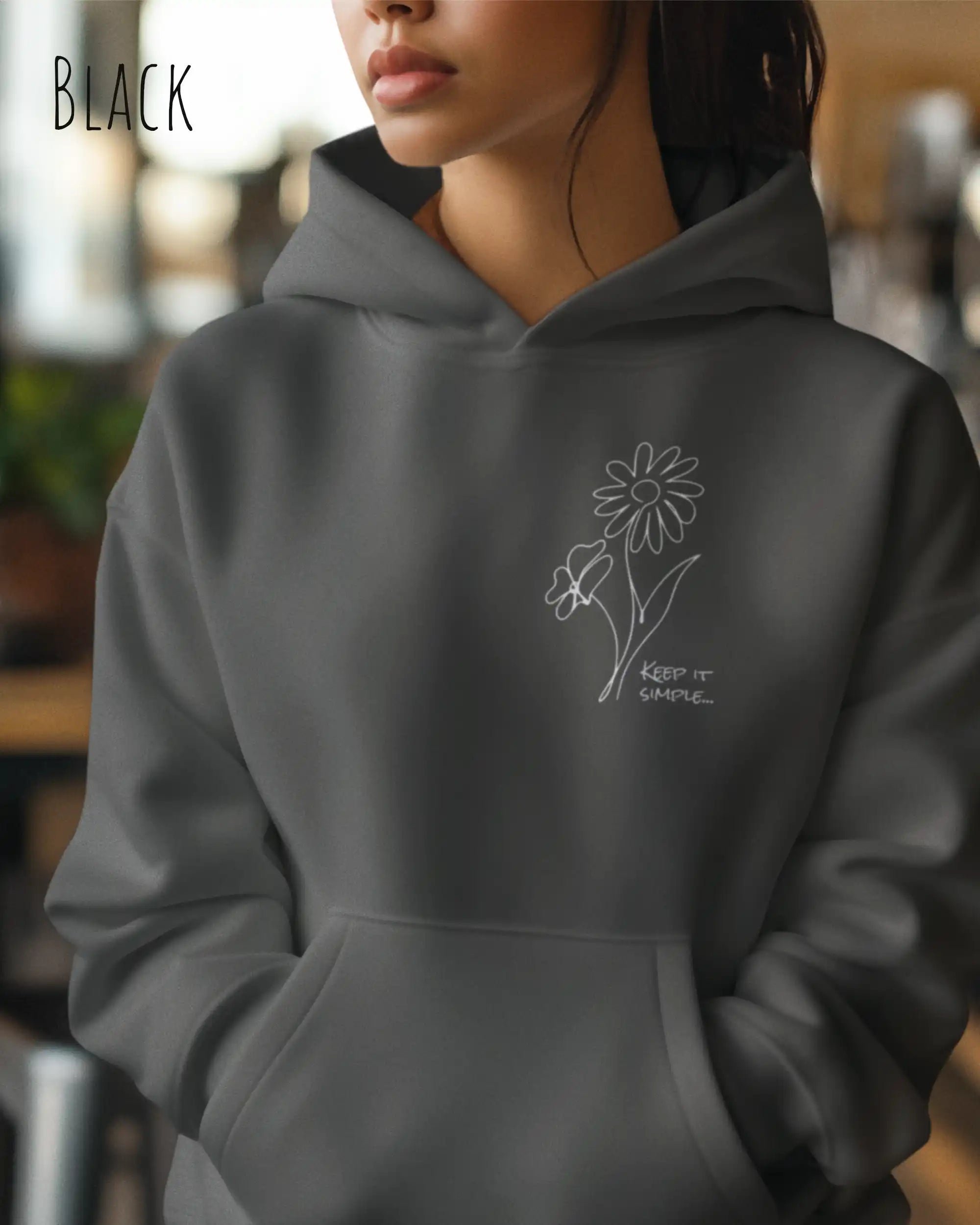 Frau trägt einen heavyweight oversized hoodie in der farbe black mit dem minimaoistischen Design keep it simple.