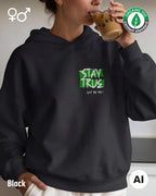eine frau trägt einen nachhaltigen oversized Kapuzenpullover in der farbe black mit dem statement "stay true" oben links auf der brust.