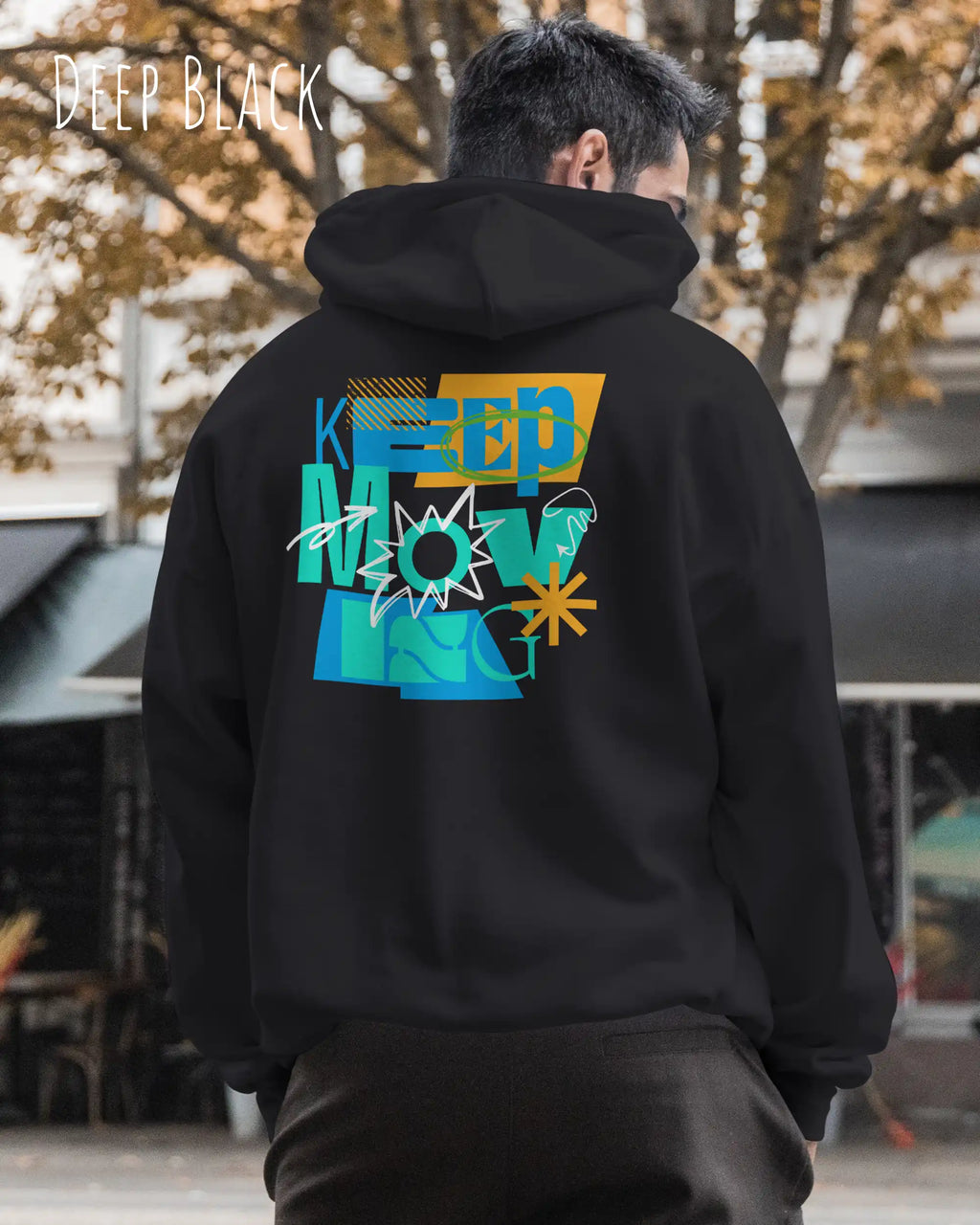 ein mann trägt einen Oversized Design-Hoodie in deep black mit der motivierenden grafik "keep moving" auf dem rücken.