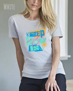 Dieses Bild zeigt eine frau, die ein feminines design-T-Shirt in der farbe white und mit der motivierenden grafik "keep moving" trägt.