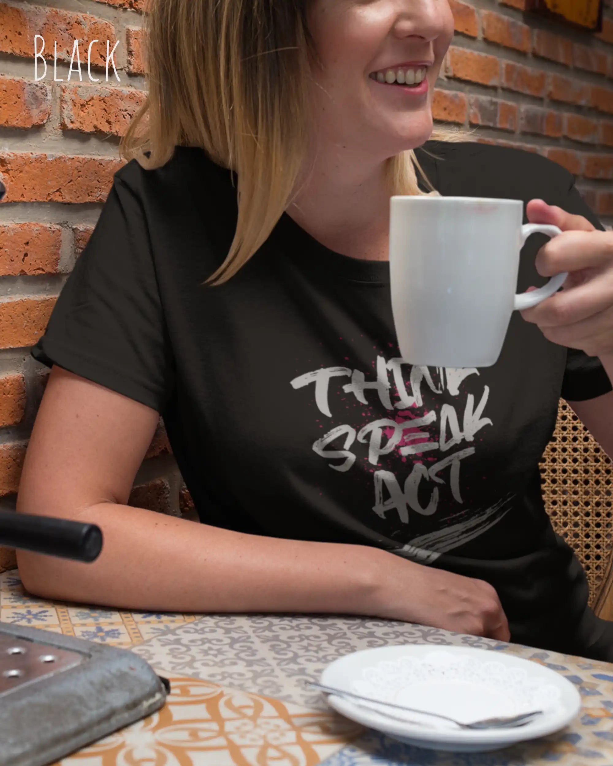 Frau im Cafe trägt das Bio-Baumwolle T-Shirt Tee Jays Urban Luxury Tee 1150 in der Farbe black mit dem Design THINK SPEAK ACT auf der Brust.
