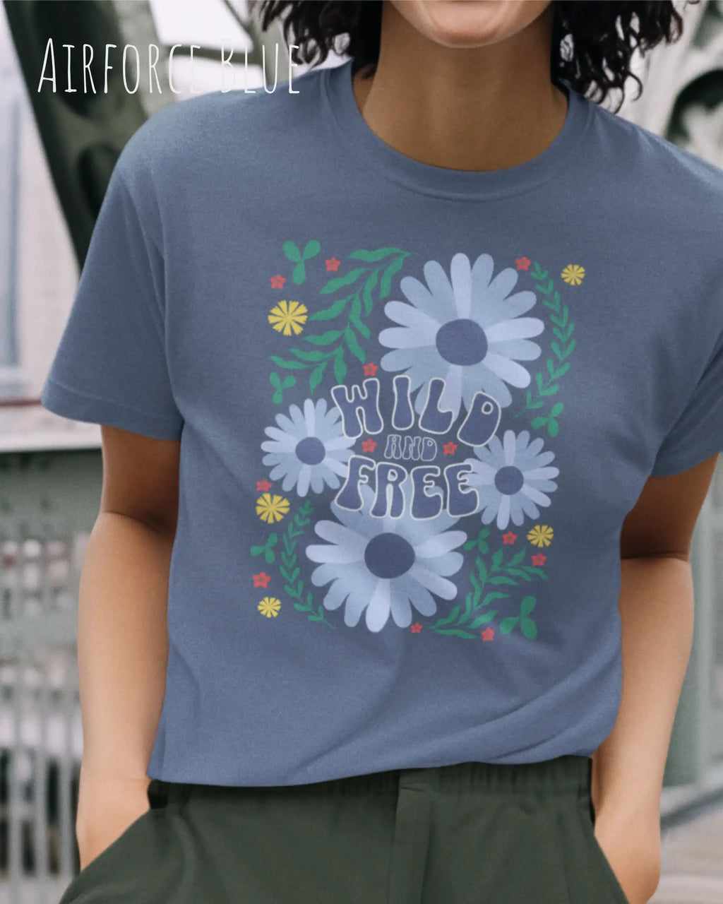 Das Bild zeigt eine Frau, die ein Design-T-Shirt in der farbe airforce blue  aus atmungsaktiver Baumwolle  mit dem statement WILD AND FREE trägt.