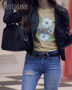 Das Bild zeigt eine Frau, die ein Design-T-Shirt in der farbe desert sand  aus atmungsaktiver Baumwolle  mit dem statement WILD AND FREE trägt.