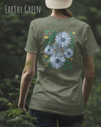 Das Bild zeigt eine Frau, die ein Design-T-Shirt in der farbe earthy green  aus atmungsaktiver Baumwolle  mit dem statement WILD AND FREE trägt.