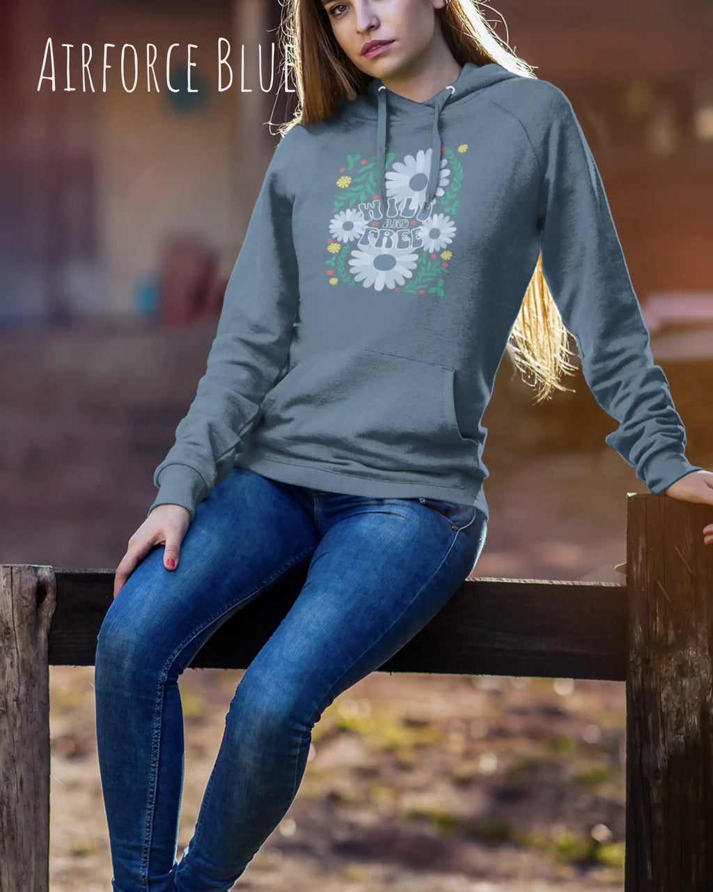 EINE FRAU TRÄGT einen damen design hoodie in der Farbe AIRFORCE BLUE mit dem STATEMENT  WILD AND FREE.