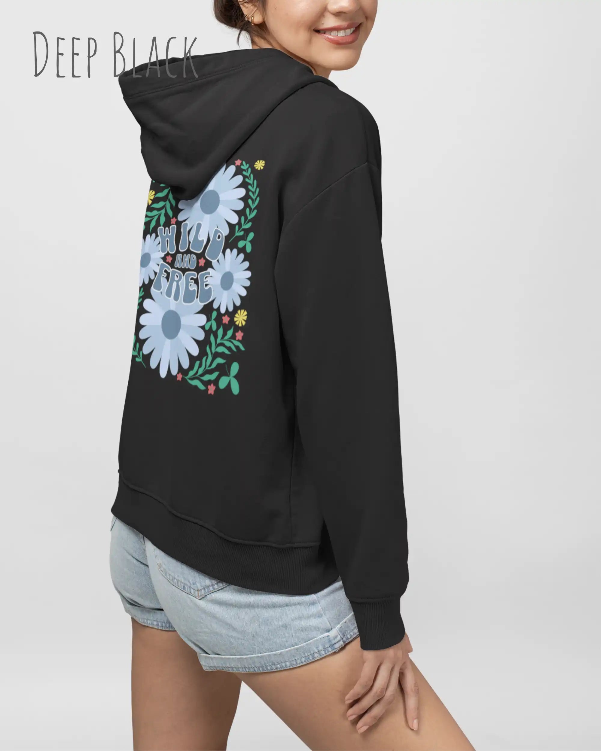 FRAU TRÄGT einen damen design hoodie in der Farbe DEEP BLACK mit dem BACKPRINT STATEMENT  WILD AND FREE.