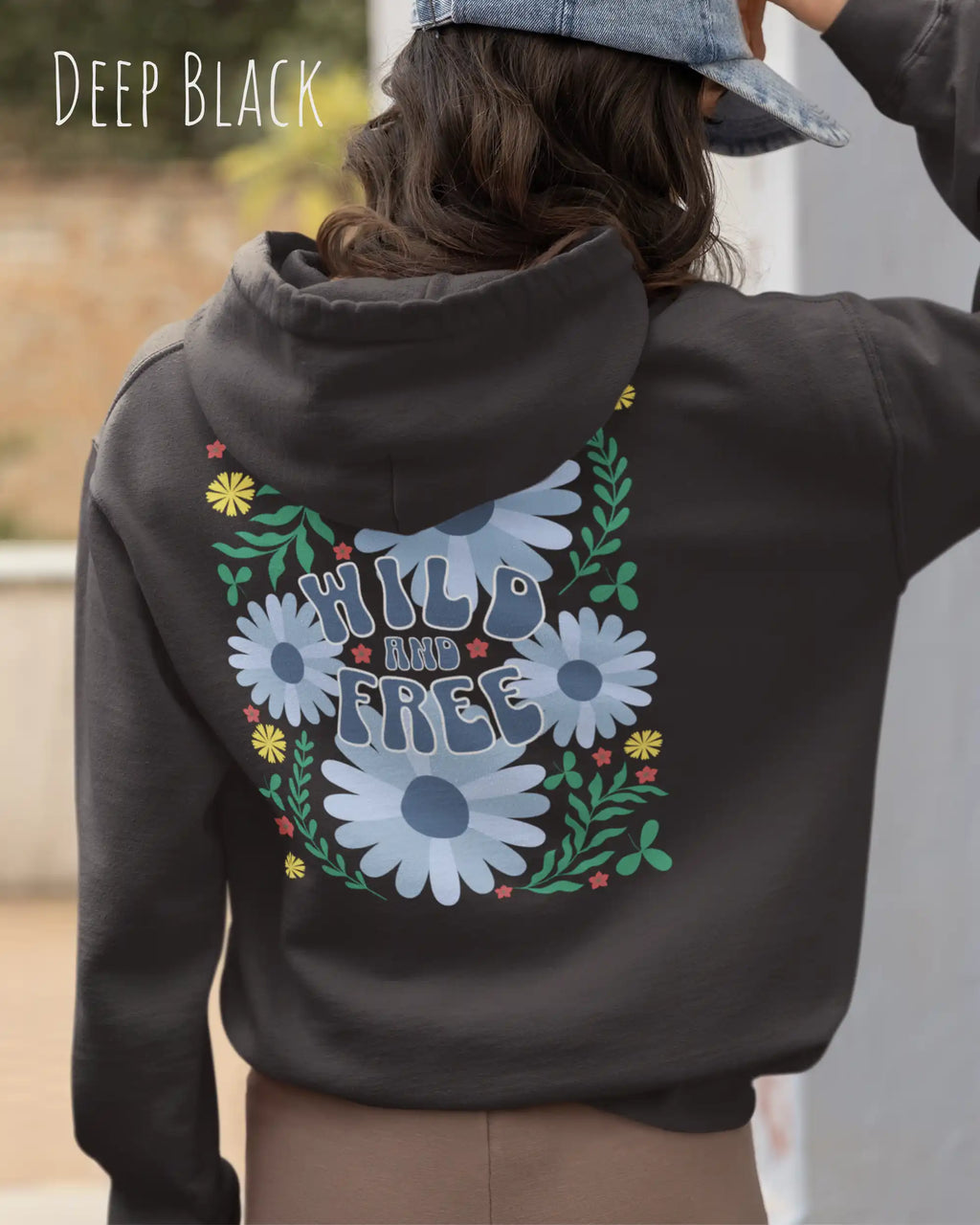 Eine Frau trägt einen Oversized Design-Hoodie in deep black mit dem Backprint-Statement wild and free,