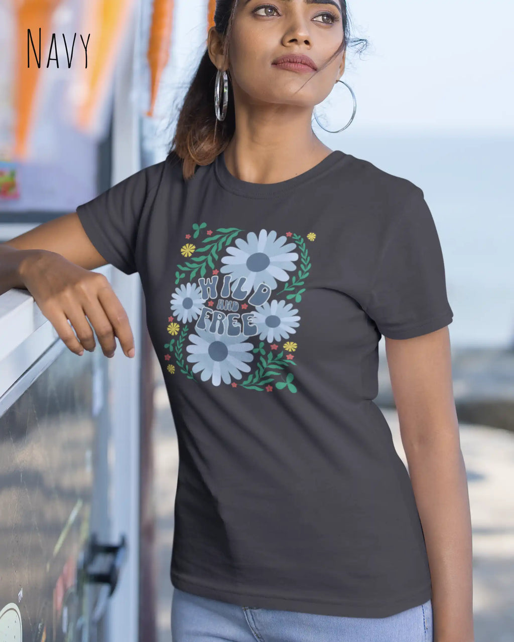 Junge frau beim klettern trägt ein feminines Basic Design-T‑Shirt  in der farbe navy mit dem motiv WILD AND FREE.