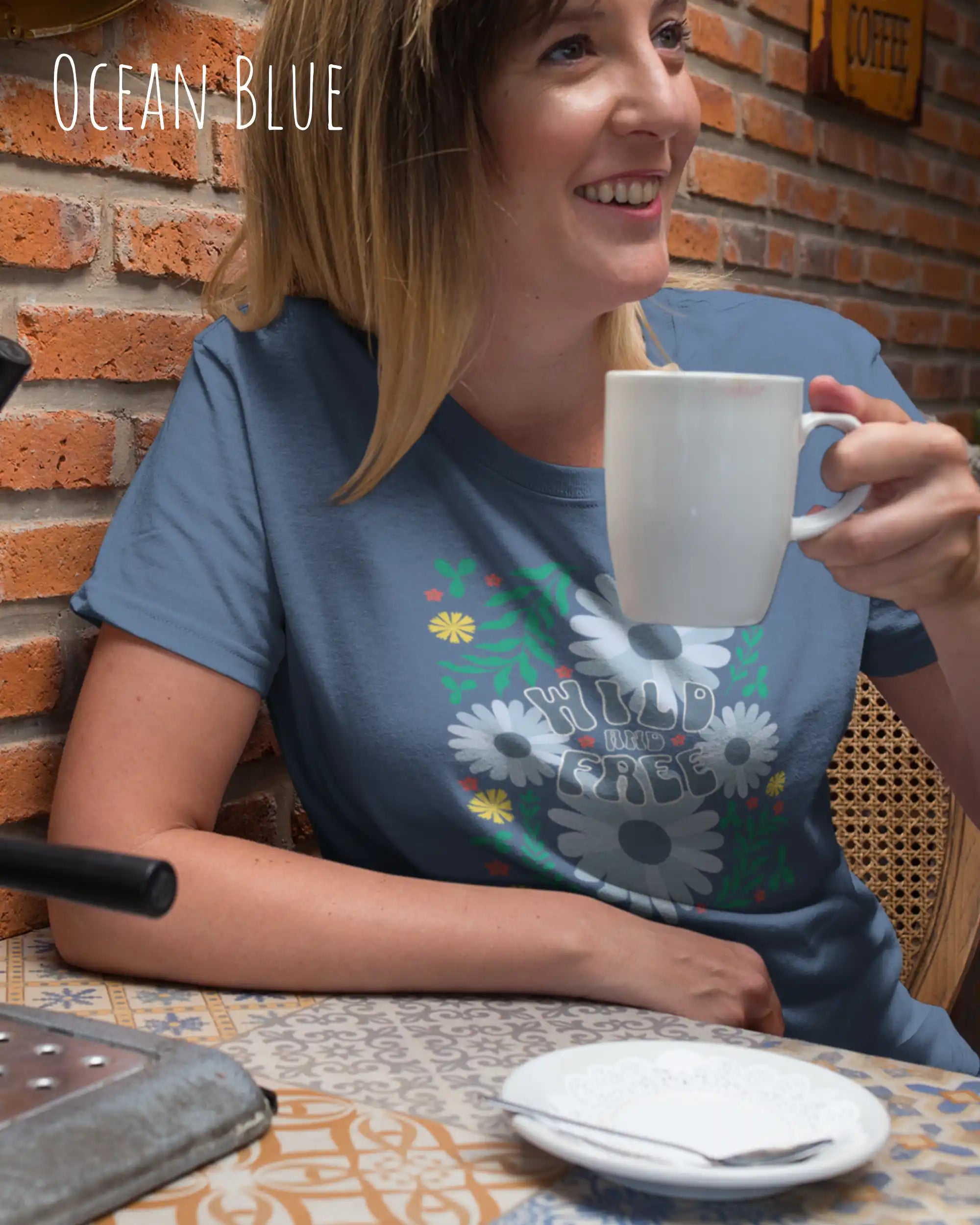 frau trägt ein design-t-shirt in der farbe ocean blue mit dem motiv wild and free im modernisierten boho-style.