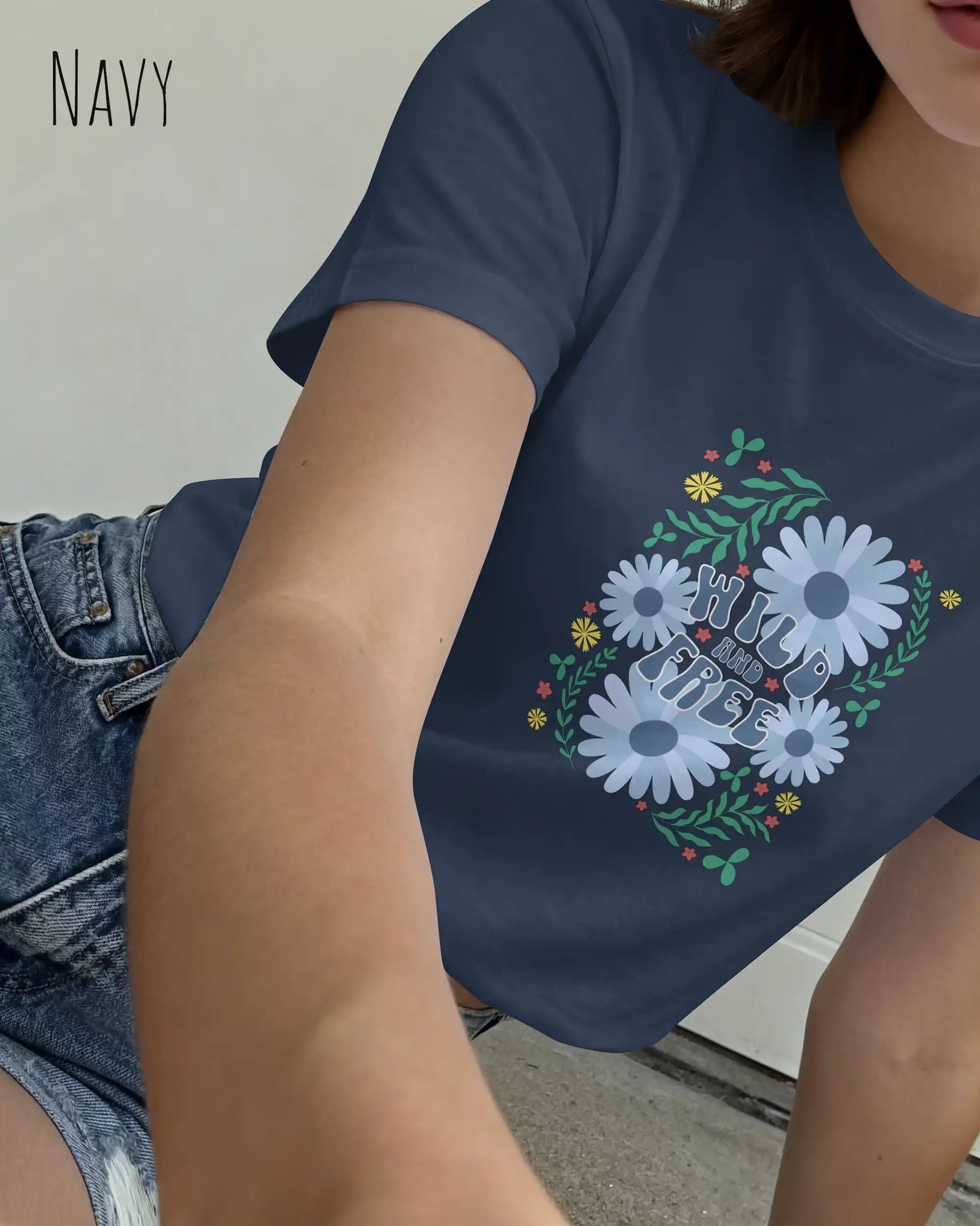 Eine Frau trägt ein T-Shirt mit dem Design Wild and free in der farbe navy.