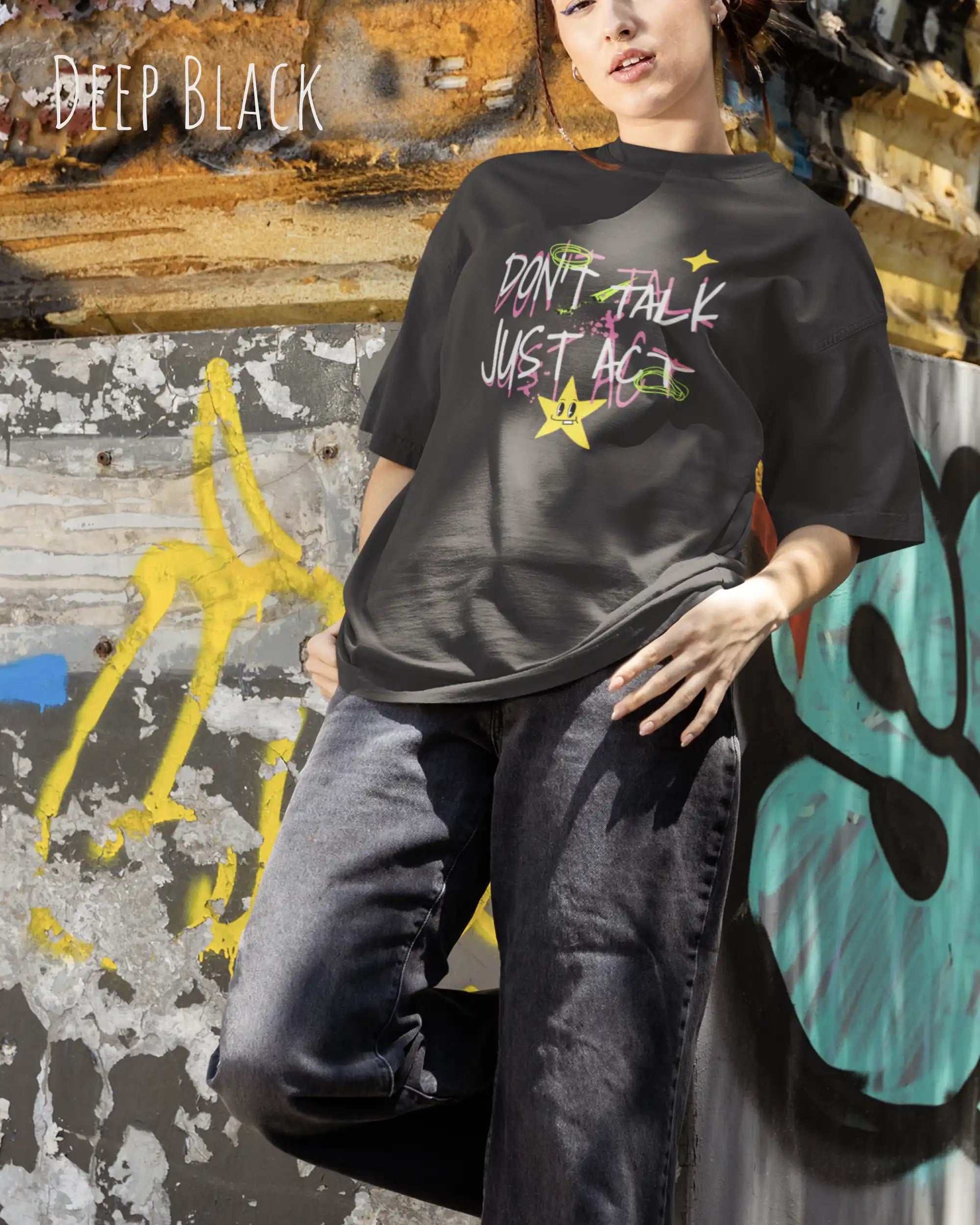 JUNGE FRAU trägt das Heavyweight Oversized T-Shirt AWDis 240 T in der Farbe DEEP BLACK mit dem STATEMENT Design DON’T TALK JUST ACT