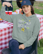EINE FRAU TRÄGT einen design hoodie in der Farbe dusty green mit dem STATEMENT don't talk just act,