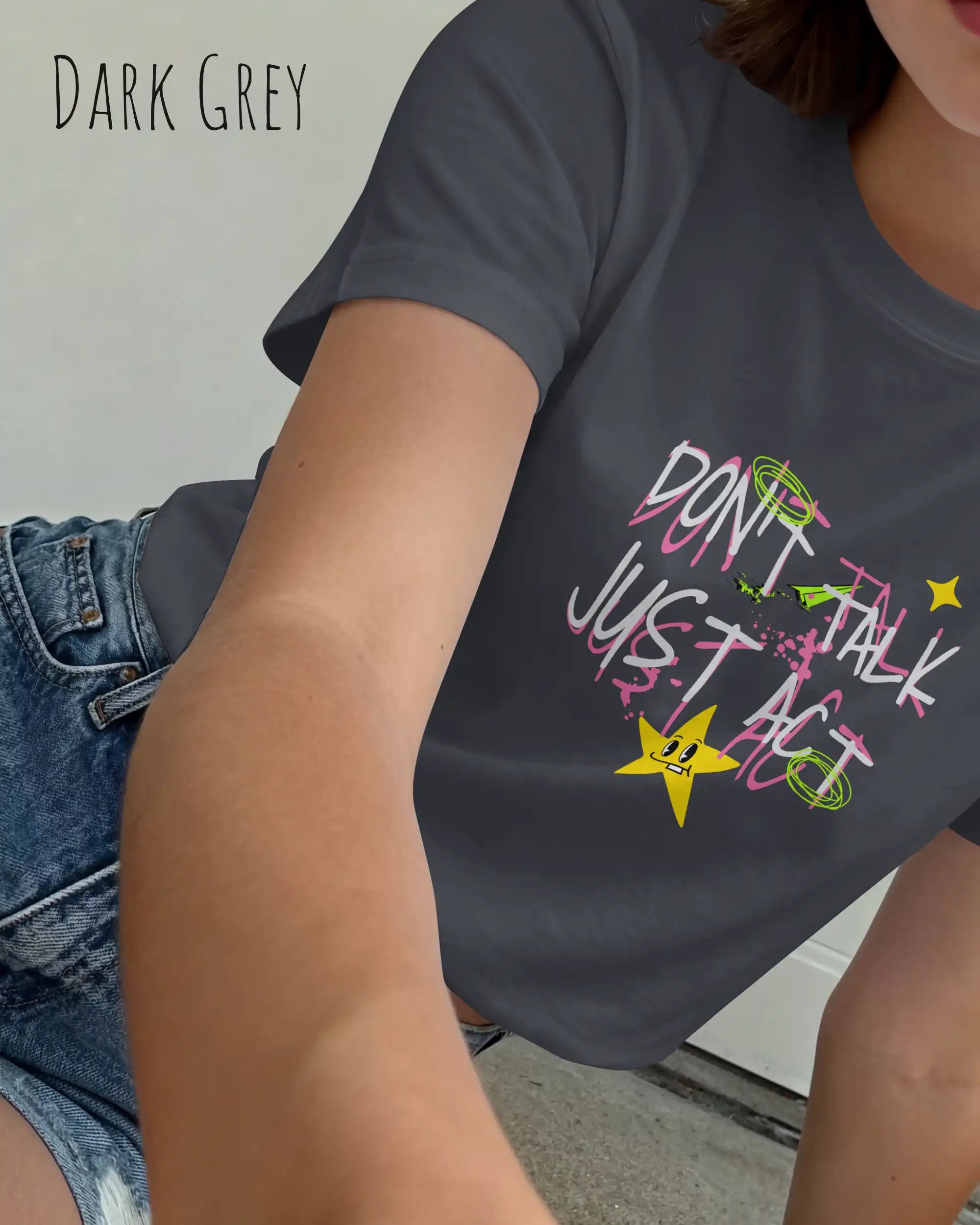 das bild zeigt eine frau, die ein feminines Design-T-Shirt in der farbe dark gREY mit dem design "Don't talk Just Act" trägt.