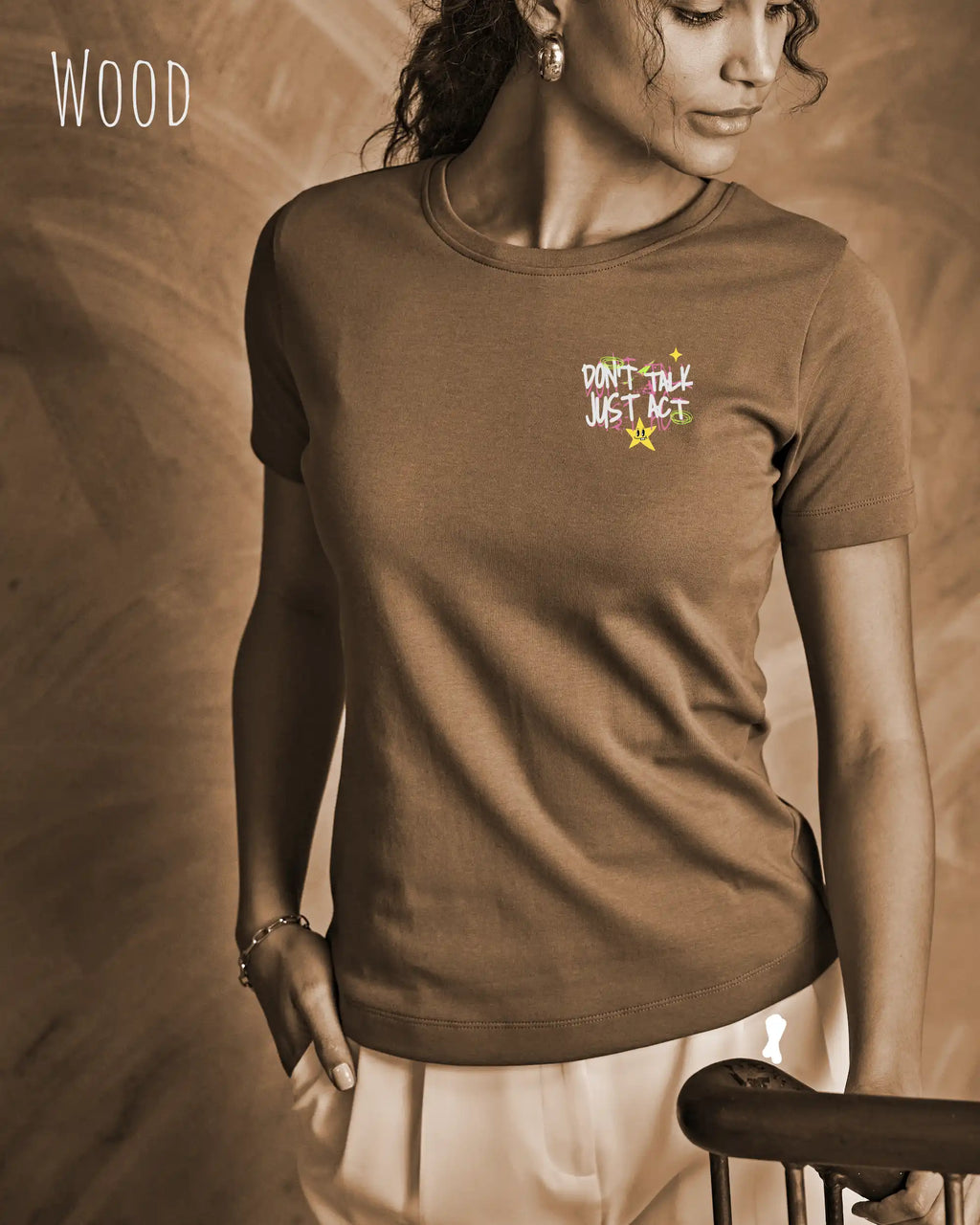 das bild zeigt eine frau, die ein feminines Design-T-Shirt in der farbe wood mit dem design "Don't talk Just Act" oben links  trägt.