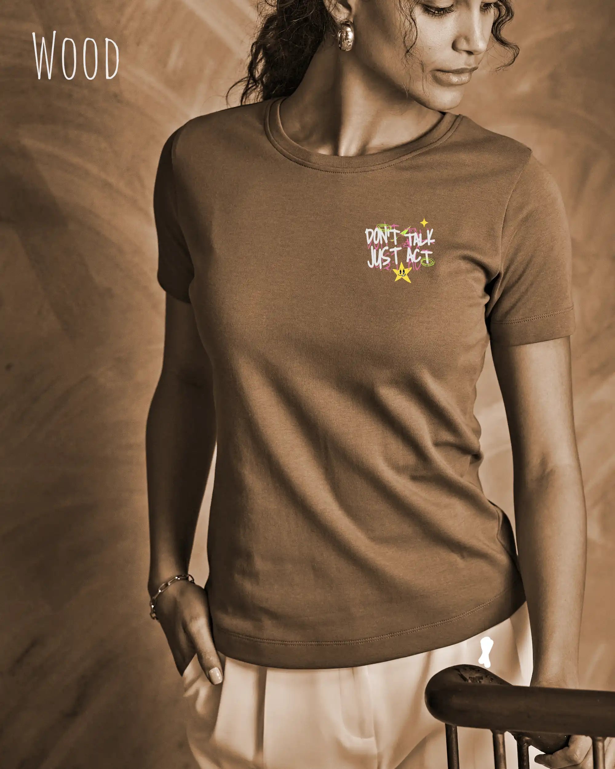 das bild zeigt eine frau, die ein feminines Design-T-Shirt in der farbe wood mit dem design "Don't talk Just Act" oben links  trägt.