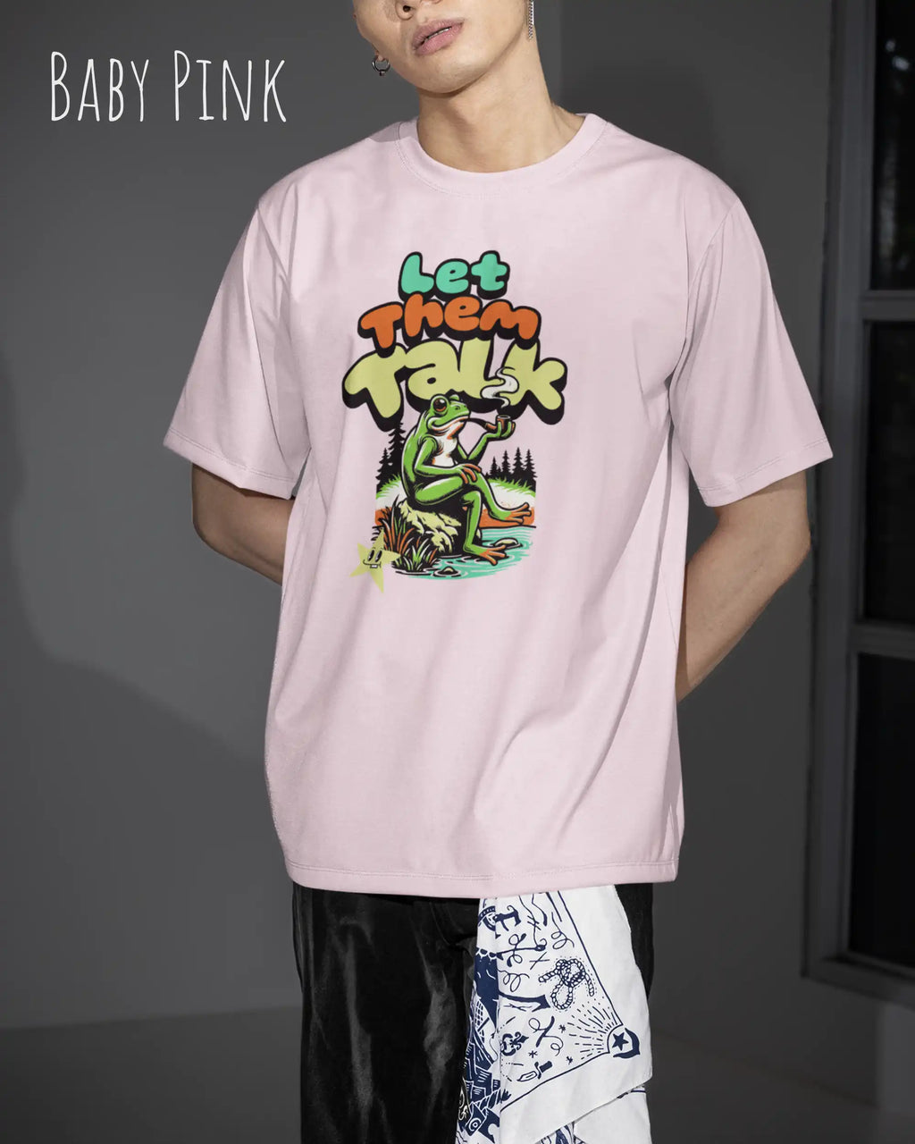 Die Abbildung zeigt eine frau  mit einem Design-T-Shirt in der Farbe baby pink und mit der Grafik let them talk.