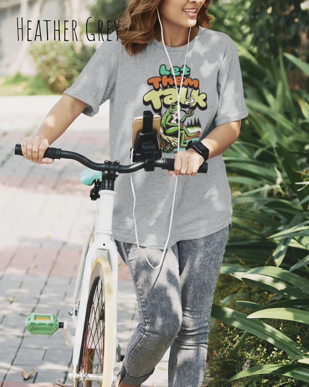 Die Abbildung zeigt eine frau mit einem Design-T-Shirt in der Farbe heater grey und mit der Grafik let them talk.