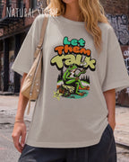 eine blonde frau trägt ein oversized heavyweight design-t-shirt in der farbe natural stone mit dem entspannten motiv let them talk - lass sie reden. 