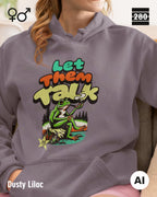 Eine frau trägt einen Design-Hoodie  in der farbe dusty lilac mit dem humorvollen motiv "let them talk".