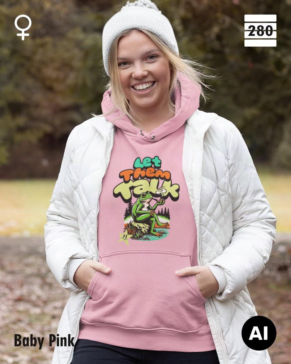 Das bild zeigt eine frau, die  einen Damen-Design-Hoodie in der farbe candyfloss pink mit dem humorvollen motiv "let them talk" trägt.