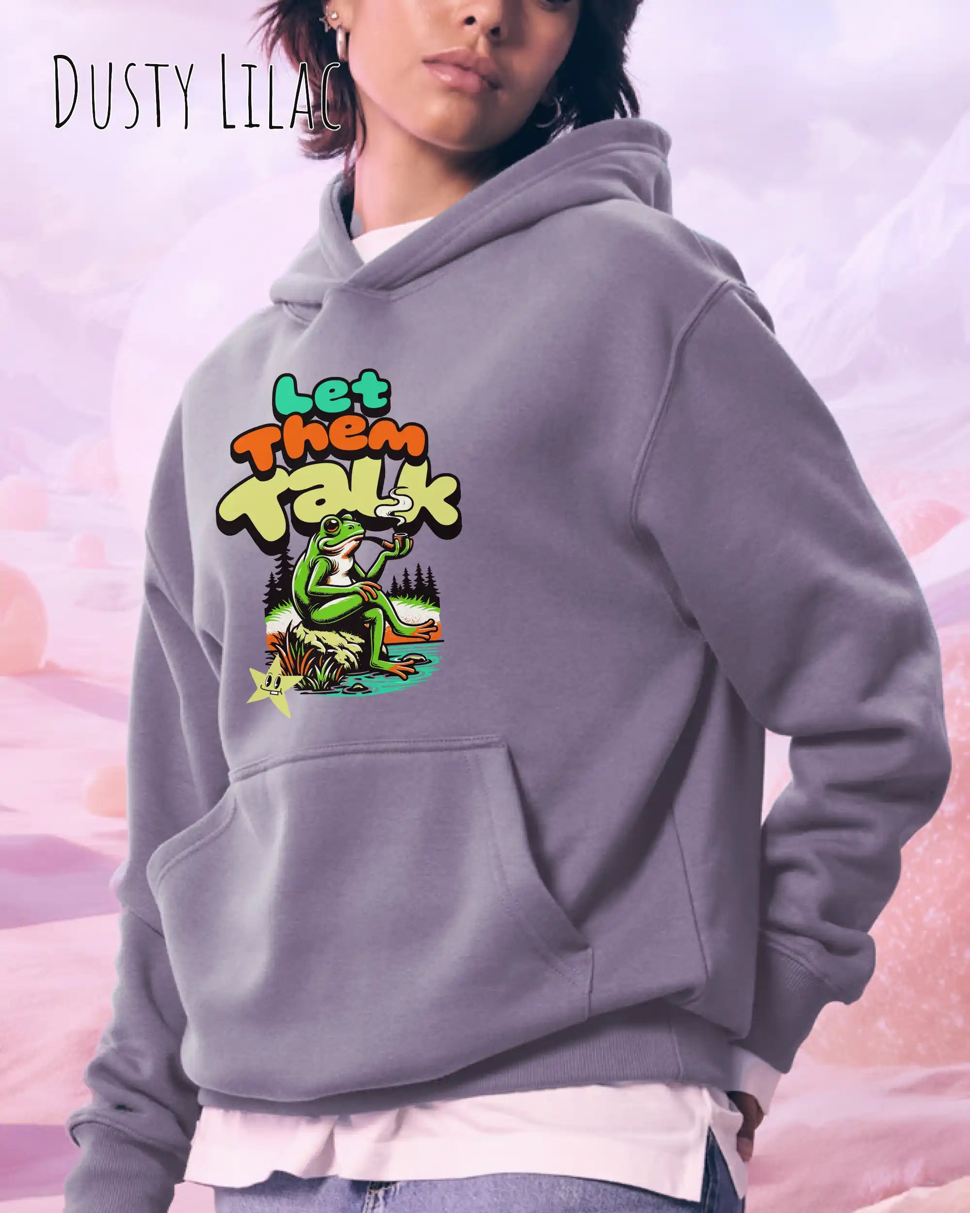 die Abbildung zeigt eine frau, die einen Oversized Design-Hoodie in der farbe dusty lilac und mit dem humorvollen motiv "let them talk" trägt.