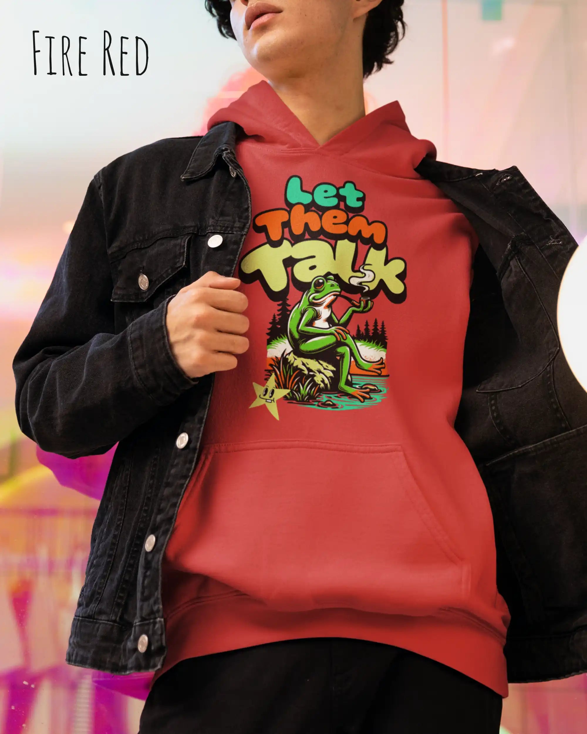 die Abbildung zeigt einen mann, der einen Oversized Design-Hoodie in der farbe fire red und mit dem humorvollen motiv "let them talk" trägt.