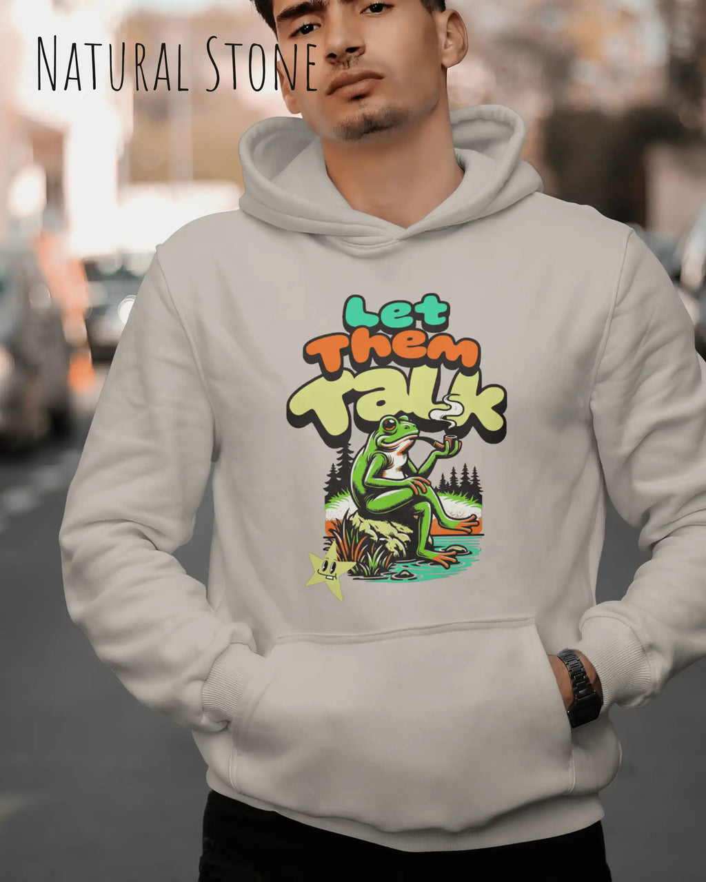die Abbildung zeigt einen mann, der einen Oversized Design-Hoodie in der farbe natural stone und mit dem humorvollen motiv "let them talk" trägt.