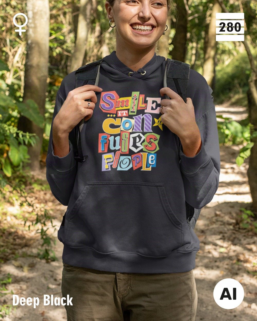 das bild zeigt eine frau, die einen leicht taillierten damen design hoodie in der farbe deep black  und mit dem farbenfrohen motiv "smile ... it confuses people" trägt.