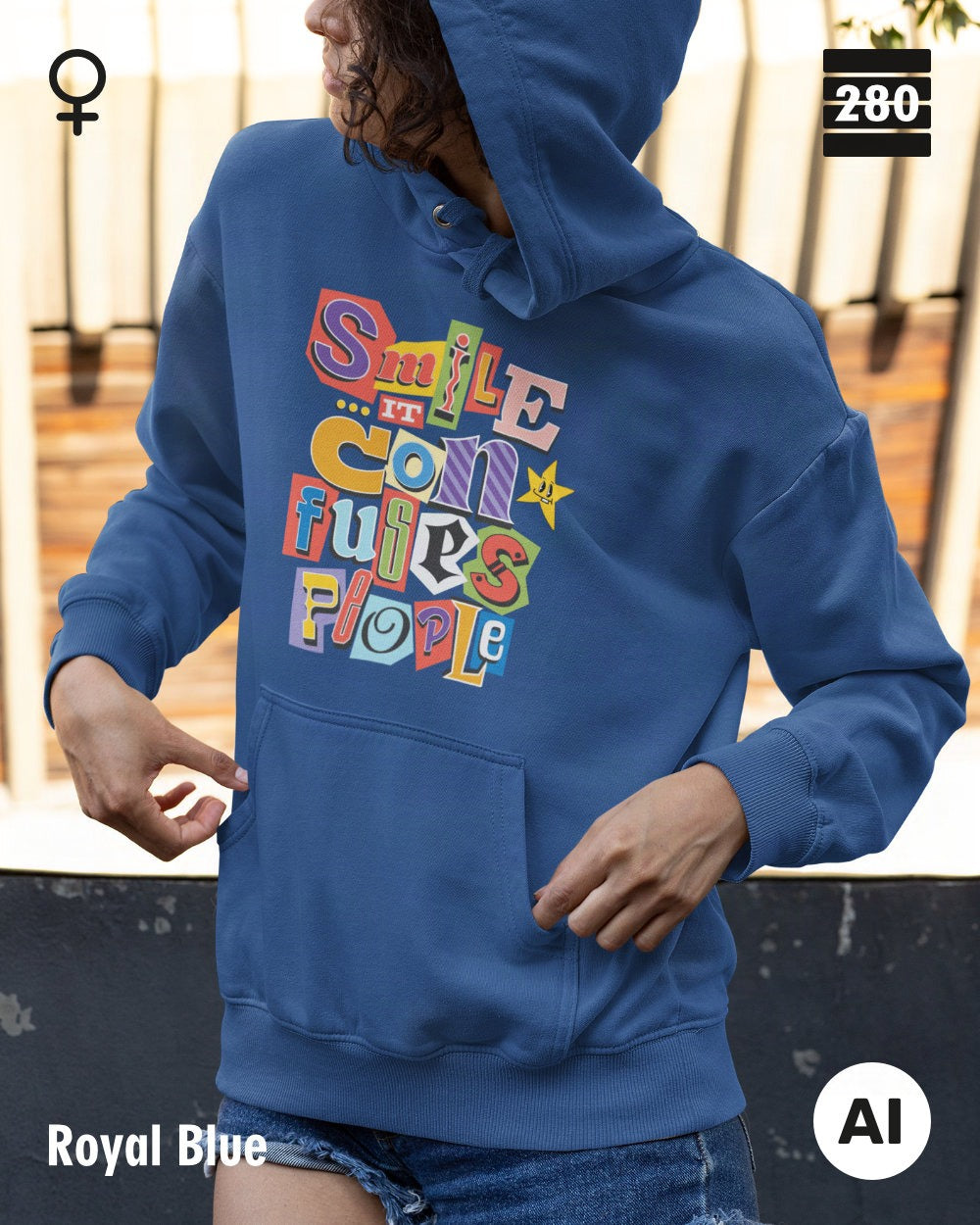 das bild zeigt eine frau, die einen leicht taillierten damen design hoodie in der farbe royal blue und mit dem farbenfrohen motiv "smile ... it confuses people" trägt