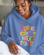 eine frau trägt einen Oversized Design-Hoodie in  atlantic blue mit der farbenfrohen grafik "Smile ... it confuses people".