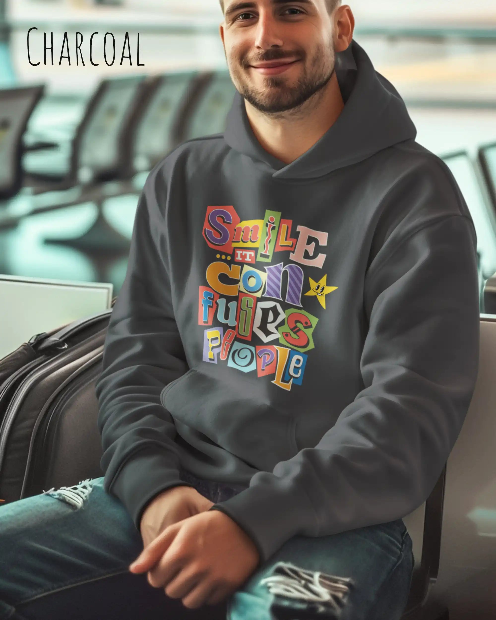 ein mann trägt einen Oversized Design-Hoodie in  charcoal mit der farbenfrohen grafik "Smile ... it confuses people".