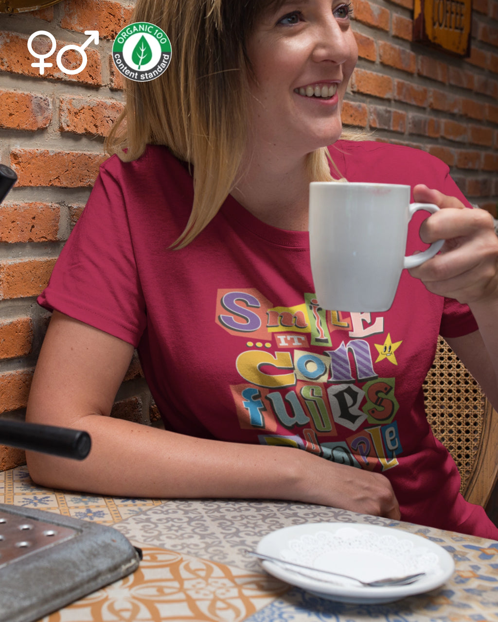 Frau im cafe trägt ein Dnachhaltiges unisex esign-T-Shirt  in red  mit dem frontprint "Smile, it confuses people".