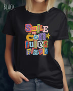 Die Abbildung zeigt eine frau, die ein feminines design-t-shirt in der farbe black mit der farbenfrohen grafik "smile ... it confuses people" trägt.