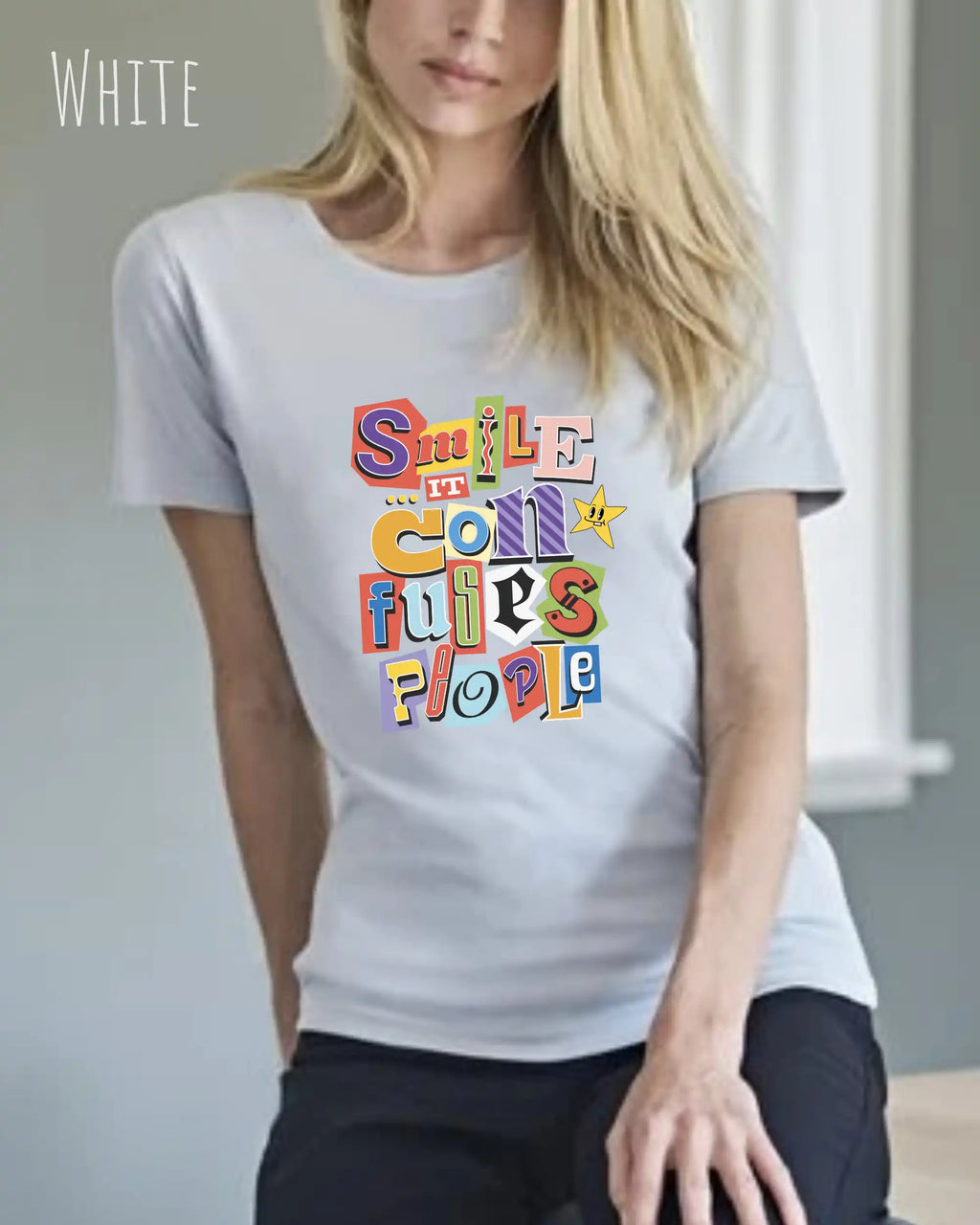 Die Abbildung zeigt eine frau, die ein feminines design-t-shirt in der farbe white mit der farbenfrohen grafik "smile ... it confuses people" trägt.